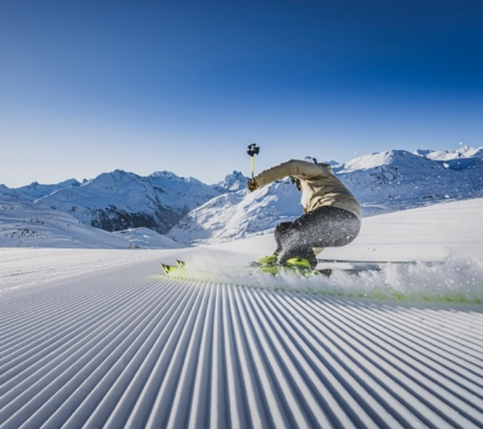 Skifahrer beim Carven auf frisch präparierter Skipiste in den Bergen